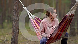 Teenage girl relaxing in hammock under trees. Female teen resting in weekend