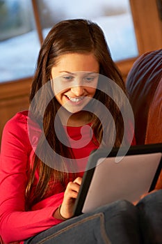 Teenage Girl Relaxing On Sofa With Tablet Computer