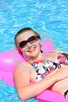 Teenage girl relaxing the in the sun on a lilo