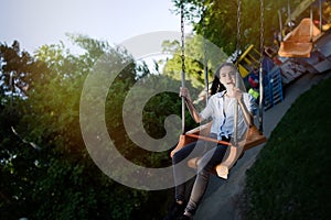 Teenage girl riding chain carousel swing at amusement park