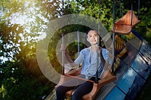 Teenage girl riding chain carousel swing at amusement park