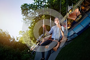 Teenage girl riding chain carousel swing at amusement park