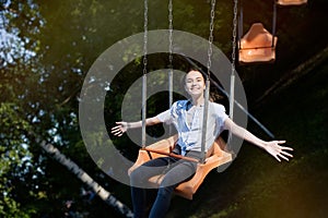 Teenage girl riding chain carousel swing at amusement park