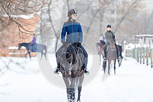 Teenage girl riding horse at the ranch in winter
