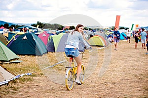 Teenage girl riding yellow bike at summer music festival