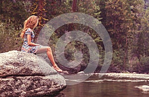 Teenage girl on rock in river