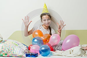 The teenage girl`s birthday is 10 years old. A girl in a festive hat lies with a gift on the bed in a children`s room, girl show