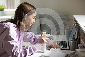 Teenage girl sanitize computer with antibacterial gel at home