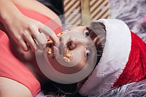 Teenage girl in a santa hat with a dirty face in sweet cream