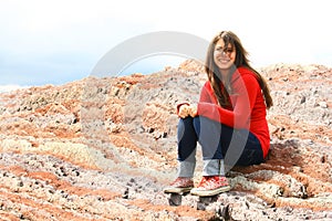 Teenage girl sat on red rocks