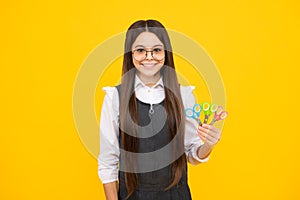 Teenage girl with scissors, isolated on yellow background. Child creativity, arts and crafts.