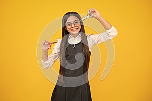 Teenage girl with scissors, isolated on yellow background. Child creativity, arts and crafts.