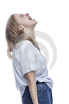 A teenage girl screams. Young pretty blonde in a white T-shirt and jeans. Depression and horror. Isolated on white background.