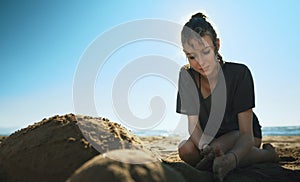 Teenage girl sculpt turtle from the sand photo