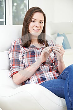 Teenage Girl Sending Text Message From Mobile Phone At Home