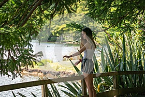 Teenage girl in shade stands by  railing looking at lake