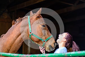 A teen girl laughs with her horse