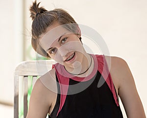 Teenage girl with short hair sitting with her head tilted to her right