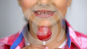 Teenage girl showing lollipop at camera, dental care concept sugar causes caries