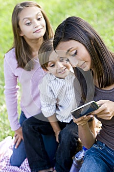 Teenage girl showing mobile phone to siblings