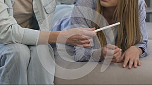 Teenage girl showing positive pregnancy test to mother, supportive parents