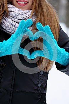 A teenage girl shows a heart gesture, close-up