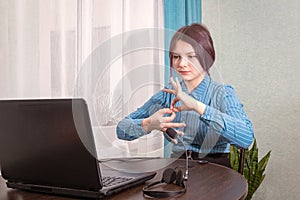 A teenage girl sits in front of her laptop learning sign language, a language for the deaf and dumb online