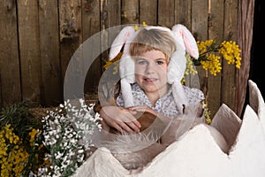 a teenage girl sits in a huge eggshell. Rabbits in the hands of a child. Easter attributes. happy easter concept. Smile