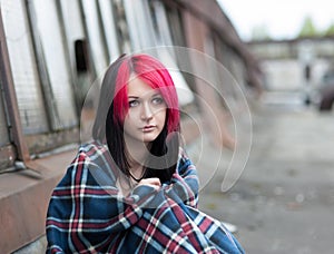 Teenage girl sitting covered with a rug