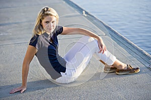 Teenage girl sitting on dock by water