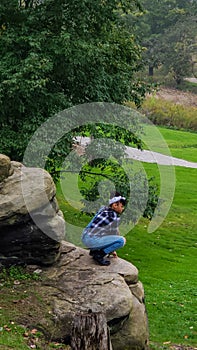 Teenage girl sitting on a edge of a cliff in the park