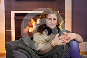 Teenage girl sitting at home at fireplace