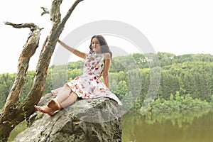 Teenage girl sitting on rock above river