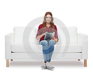 Teenage girl sitting on sofa with tablet pc