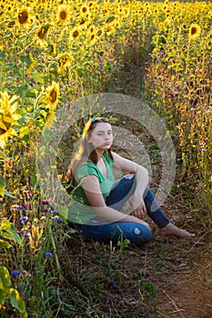 Teenage girl sitting among sunflowers