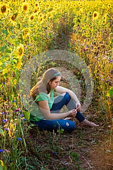 Teenage girl sitting in sunflowers