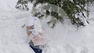 Teenage girl sitting under snow pine tree.