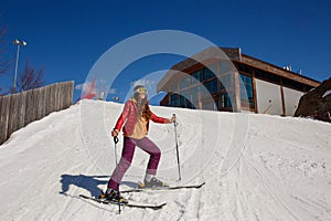 Teenage girl on skis stands on a mountainside