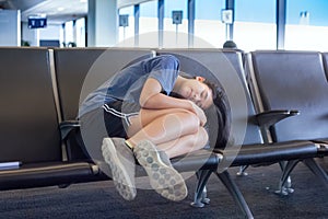 Teenage girl sleeping on airport bench in terminal, tired