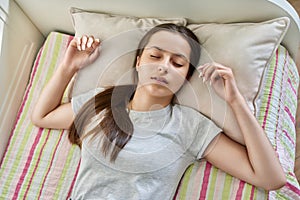 Teenage girl sleeping at home in bed, calm peaceful female teenager with closed eyes