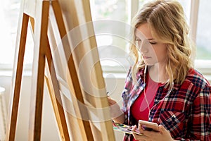 Teenage girl with smartphone at art school studio