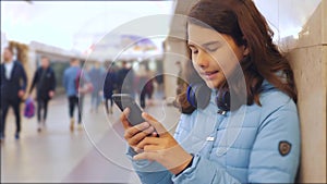 Teenage girl with smartphone and headphones waiting subway lot of people crowd underground. metro underground lifestyle