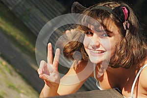 Teenage girl smiles positively and shows victory sign. Positive smile concept under different circumstances