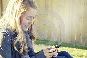 Teenage girl smiling while using a cell phone