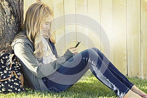 Teenage girl smiling while using a cell phone