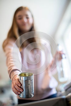 Teenage Girl Sorting Recycling Into Kitchen Bin At Home