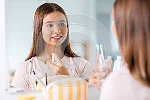 teenage girl spraying perfume at bathroom