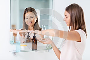 teenage girl squeezing liquid soap at bathroom