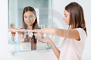 teenage girl squeezing liquid soap at bathroom