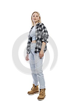 A teenage girl is standing. A cute blonde with freckles on her face wearing jeans, a plaid shirt and yellow shoes. Full height.